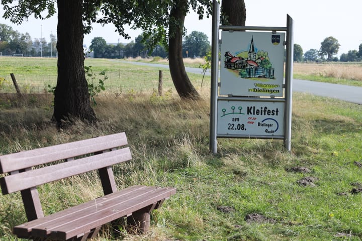 Hinweisschild zum 24. Kleifest neben einer Bank am Dielinger Klei