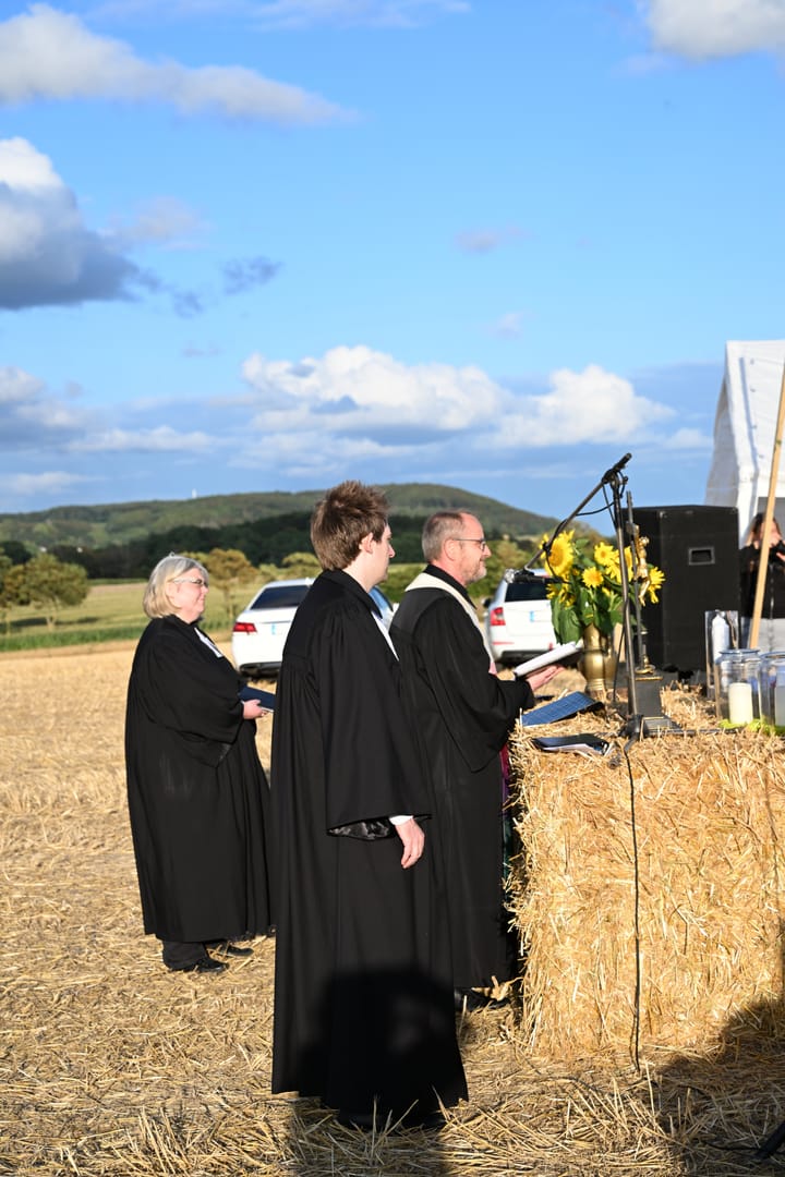 Geistliche vor dem Strohballenaltar unter freiem Himmel