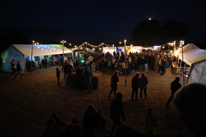 Beleuchtetes Kleifest mit Lichterketten und Besuchern bei Nacht