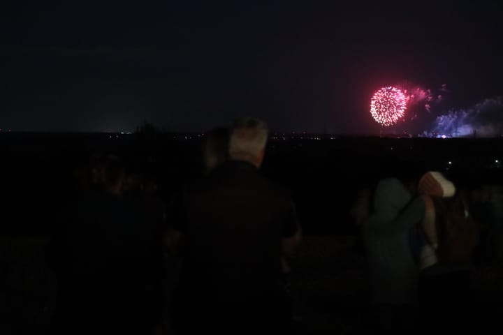 Rotes Feuerwerk über dem Kleifest mit Besuchern im Vordergrund
